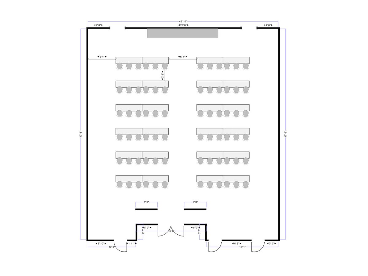 A room layout showing rows of desks (likely a conference or classroom) with a stage or podium at the top. The space has multiple seating rows and an entrance at the bottom center.